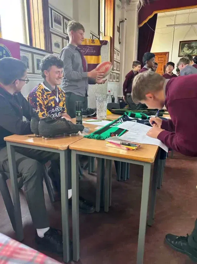 De La Salle students at a classroom table with a teacher leaning in