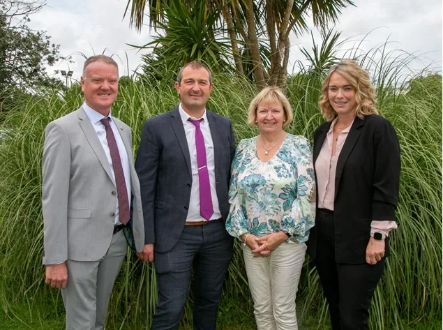 The Principal and Deputy Principals of De La Salle College standing outdoors in front of the college